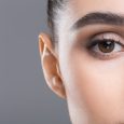 Half-face portrait of young beautiful woman with perfect skin, closeup, empty space