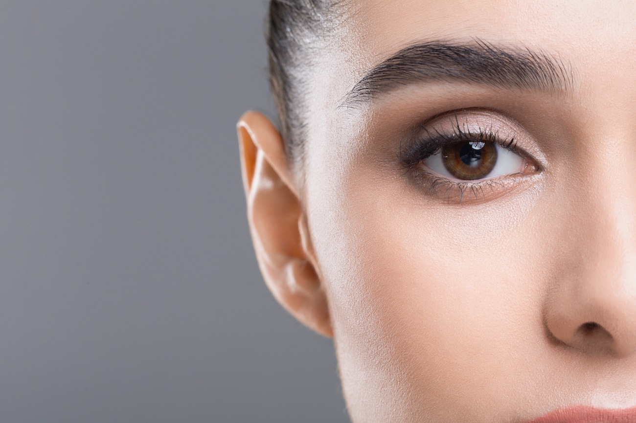 Half-face portrait of young beautiful woman with perfect skin, closeup, empty space